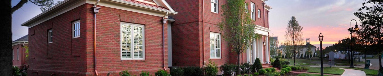Red brick house with white trim and a manicured lawn at sunset