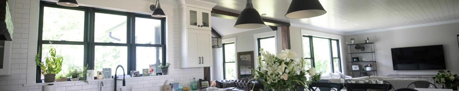 Kitchen detail showing a professional-grade stainless steel range with a custom wooden range hood and flanked by white cabinetry.