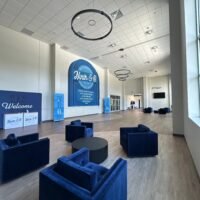 Two-story lobby at Ninth & O Baptist Church with blue lounge seating, welcome desk and Ninth & O wall graphic