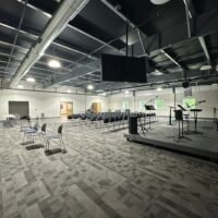 Flexible worship and event space at Ninth & O Baptist Church with stage, chair seating and exposed ceiling