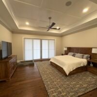 large bedroom with bed, ceiling fan, nightstands, and a tv