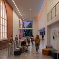 Interior rendering of a Franklinton High School corridor with exposed brick, tall arched window and student seating