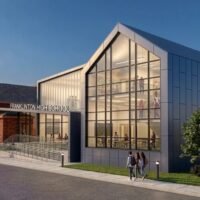 Evening rendering of the Franklinton High School entrance with students walking past the glass gable addition