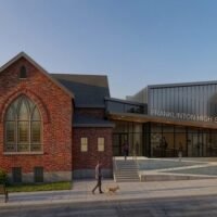Daytime rendering of Franklinton High School showing the restored brick church and new metal-clad addition along the street