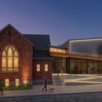 Rendering of Franklinton High School at dusk, showing the historic brick church building joined to the new glass and metal addition