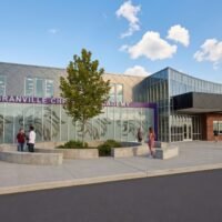 Daytime rendering of the Granville Christian Academy entrance with lion graphics on the glass, plaza seating and a young tree